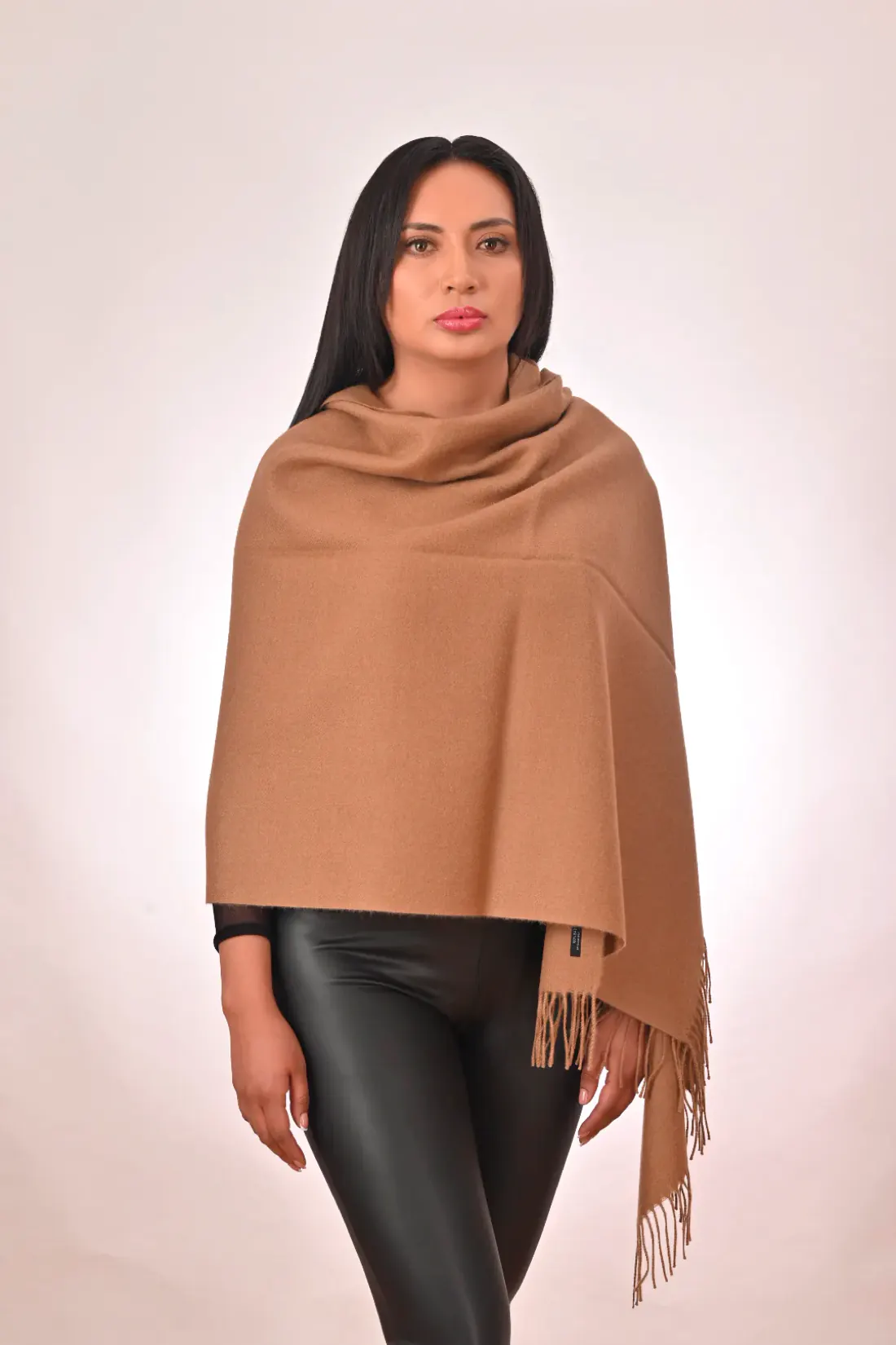 Modelo con una chalina color camel con flecos sobre los hombros