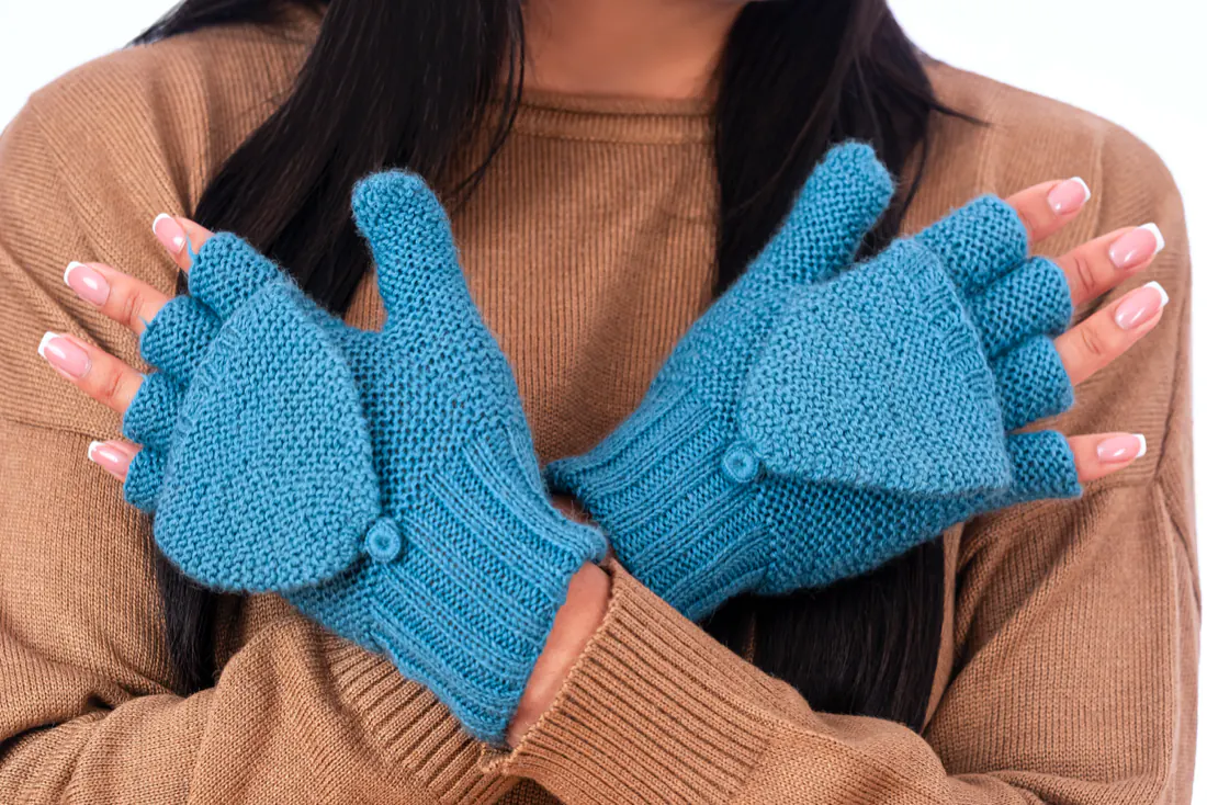 Manos cruzadas con guantes celestes sin dedos y tapa con botón
